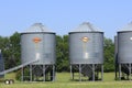 Stormor Grain bins in a farm field with blue sky, grass and tree`s in Kansas. Royalty Free Stock Photo