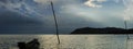 Stormy clouds over the sea, lonely boat silhouette in water, dramatic sky during sunset, no people. Tourism and travelling concept Royalty Free Stock Photo