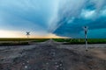 Stormy crossing with squall line converging on dirt road