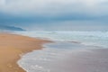 Stormy ocean, sandy beach, and cloudy sky in an overcast day