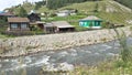 A stormy river and bright wooden rural houses in the Altai. Summer trip to Siberia in Russia