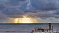 Stormy sea and dark blue clouds with gaps sun's rays, view from shore Royalty Free Stock Photo