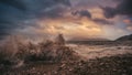 Stormy sea waves on the seashore against the beach and backdrop of the setting sun and sky with clouds