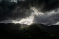 Stormy skies and a bright sun trace light over The Langdale Pikes in the English Lake District Royalty Free Stock Photo