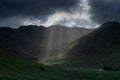 Stormy skies and a bright sun trace light over The Langdale Pikes in the English Lake District Royalty Free Stock Photo