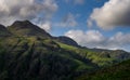 Stormy skies and a bright sun trace light over The Langdale Pikes in the English Lake District