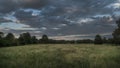 Stormy skies, green meadow, trees in the country