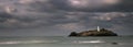 Stormy skies over Godrevy Lighthouse on Godrevy Island in St Ives Bay with the beach and rocks in foreground, Cornwall uk