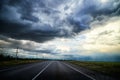 Stormy and stormy sky with gloomy dark clouds over the field and road. Dramatic landscape. The concept of traveling in