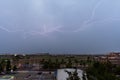 Stormy sky with several huge lightnings bolts on the outskirts of a city over agricultural fields Royalty Free Stock Photo