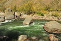 A stormy stream of a turquoise mountain river, bending around stones, flows in a rocky channel Royalty Free Stock Photo