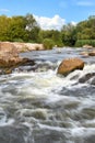 Stormy streams of water wash over the rocky banks of the river, overcoming rapids on a bright summer day, vertical image Royalty Free Stock Photo