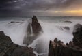 Stormy sunrise and waves crash over sea stacks