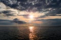 Stormy sunset over the sea. The rays of the sun through the gloomy clouds, the reflection of the sun in the water. Royalty Free Stock Photo