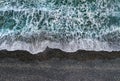 Stormy waves with white sea foam breaking on dark sandy beach, view from directly above Royalty Free Stock Photo