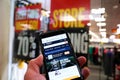 Smartphone with online retailer Amazon homepage in hand of customer