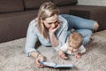 Story time mom little baby and woman reading and showing images in a book laying on floor Royalty Free Stock Photo