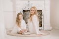 Story Time with Mother and Daughter in Front of Fireplace. Pretty family with book. Mom and child sitting close and Royalty Free Stock Photo