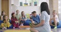 Storytime elementary or primary school teacher reading a story to a group of children in a daycare center.