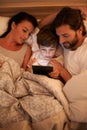 Storytime in the modern age. A shot of a little boy using a tablet while lying in bed.