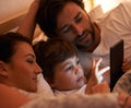 Storytime in the modern age. A shot of a little boy using a tablet while lying in bed.