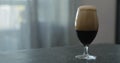 Stout beer drops slide from tulip glass on terrazzo countertop with copy space