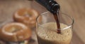 Stout beer poring into glass with bagels on background