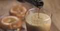 Stout beer poring into glass with bagels on background