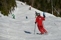 Stowe resort staff in red suit and Group of skiers seen from behind making a turn in Stowe Mountain resort in Vermont