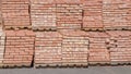 Stowed on top of each other are two rows of wooden pallets, standing with stacks of red bricks stacked on them in several levels