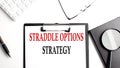 STRADDLE OPTIONS STRATEGY text written on paper clipboard with office tools