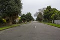 Straigh road in the suburbs with trees surrounding Royalty Free Stock Photo