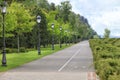 Straight asphalt road and bike path through the park with many beautiful vertical vintage lights Royalty Free Stock Photo