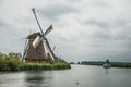 Straight canal with windmills and boat in a cloudy day at Kinderdijk. Royalty Free Stock Photo