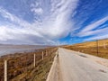 Straight country road among mountains and lake with beautiful cloudy sky background in gahai National Nature Reserve park Royalty Free Stock Photo