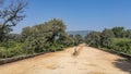 A straight dirt road goes forward. There are concrete curbs on the roadsides Royalty Free Stock Photo