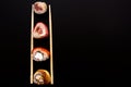 Straight parallel vertical lines of sushi and chopstick on black background