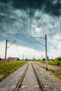 Straight railroad with dark cloudy sky