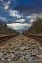 Straight railroad in the forest under a cloudy sky Royalty Free Stock Photo