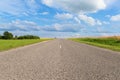 Straight road extending beyond the horizon to blue sky with ornate clouds