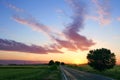 Straight road through green fields and colorful sunset Royalty Free Stock Photo