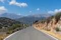 A straight road through mountains on a sunny day. Mountains in the distance. Royalty Free Stock Photo