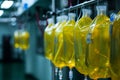 A straight row of brightly colored yellow plastic bags hanging from metal hooks against a white background, Catheters and IV bags