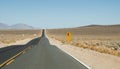 Straight section of Saline Valley Road and yellow traffic sign Royalty Free Stock Photo
