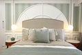 Straight show of a main bed with a large white circular headboard and lighted ceiling mounted side lamps