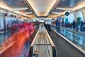 Straight on view of crowded moving sidewalks with artistic red blur showing movement