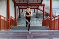 Straight view of young athletic slim beautiful woman running up stairs doing cardio interval training in black fashionable