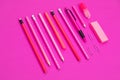 Straightly arranged group of pink color writing equipment on pink surface isolated