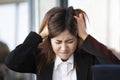 Strained businesswoman looks grave and so stressful with her working plan and holding the head with hands, failure and stress