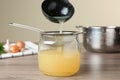 Straining delicious broth through sieve on wooden table